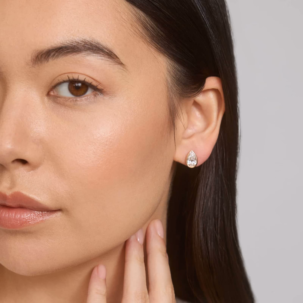 Pear diamond earring stud — yellow gold lifestyle, ear close-up