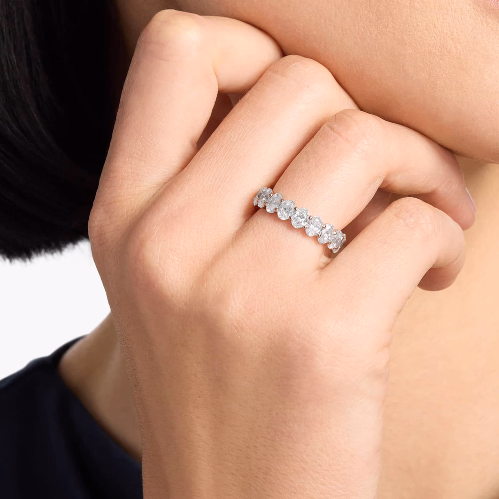 Oval diamond eternity ring in rose gold — lifestyle photograph showing a 4ct oval cut lab-grown diamond eternity band in 14K rose gold, showing the full-circle diamond coverage and warm rose gold setting that requires no rhodium plating maintenance over time