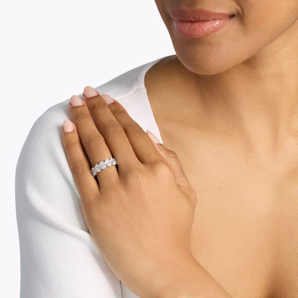 Oval diamond eternity ring in rose gold — lifestyle photograph showing a 7ct oval cut diamond eternity band in 14K rose gold with large matched oval diamonds set all the way around the full shank, demonstrating the dramatic visual weight of a high-carat-weight full oval eternity ring