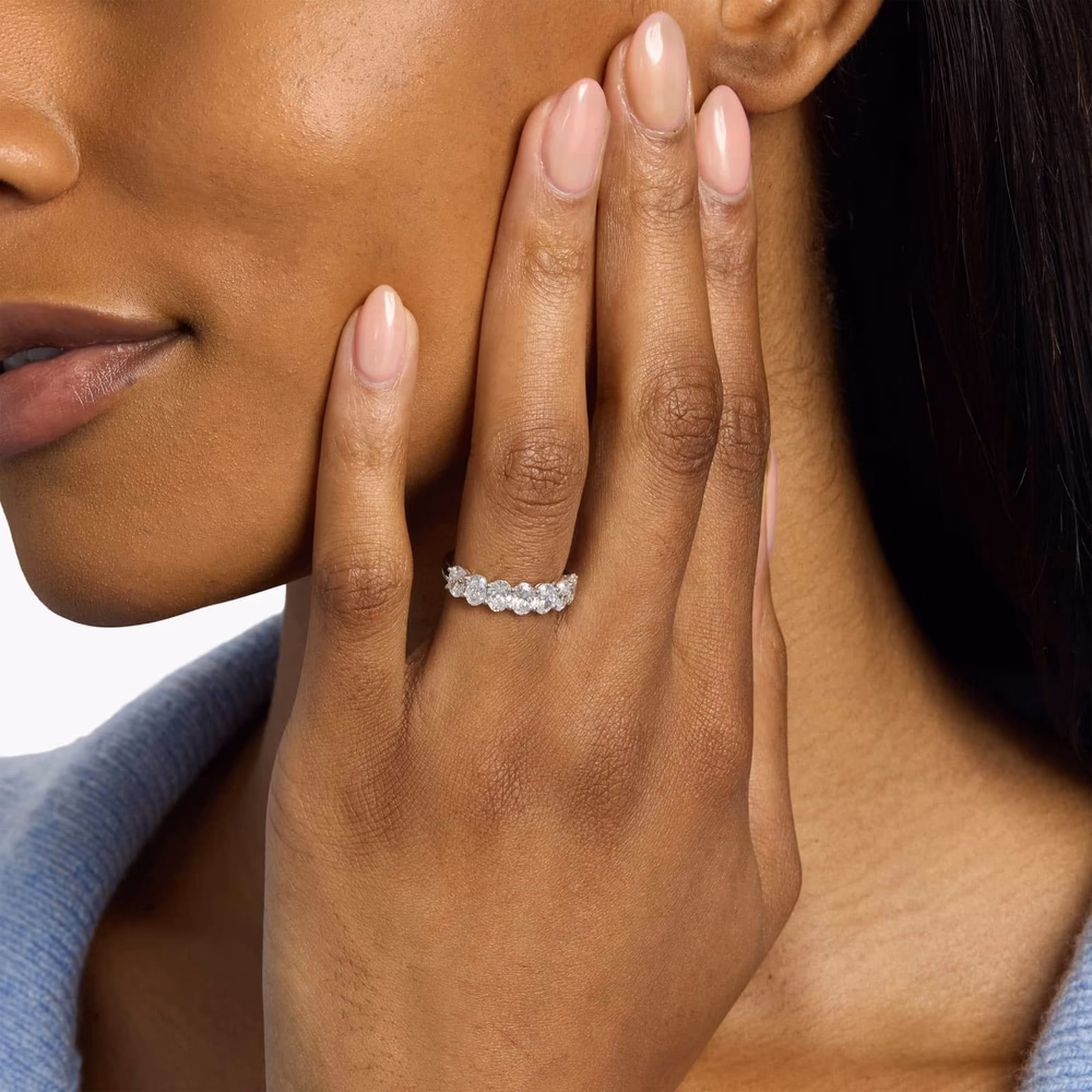 Oval Cut Eternity Ring in 14K White Gold — most-reviewed oval diamond wedding band on Blue Nile with 15 verified buyer reviews, showing matched oval-cut diamonds running all the way around the white gold shank in a lifestyle setting