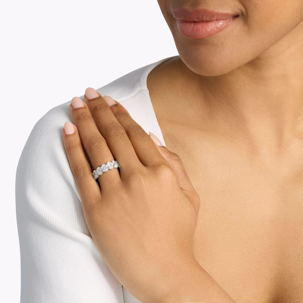 Oval diamond eternity ring in yellow gold — lifestyle photograph showing a 7ct oval cut lab-grown diamond eternity band in 14K yellow gold, illustrating how warm yellow gold neutralizes H-I diamond tint via simultaneous contrast, making the stones appear whiter than their grading suggests