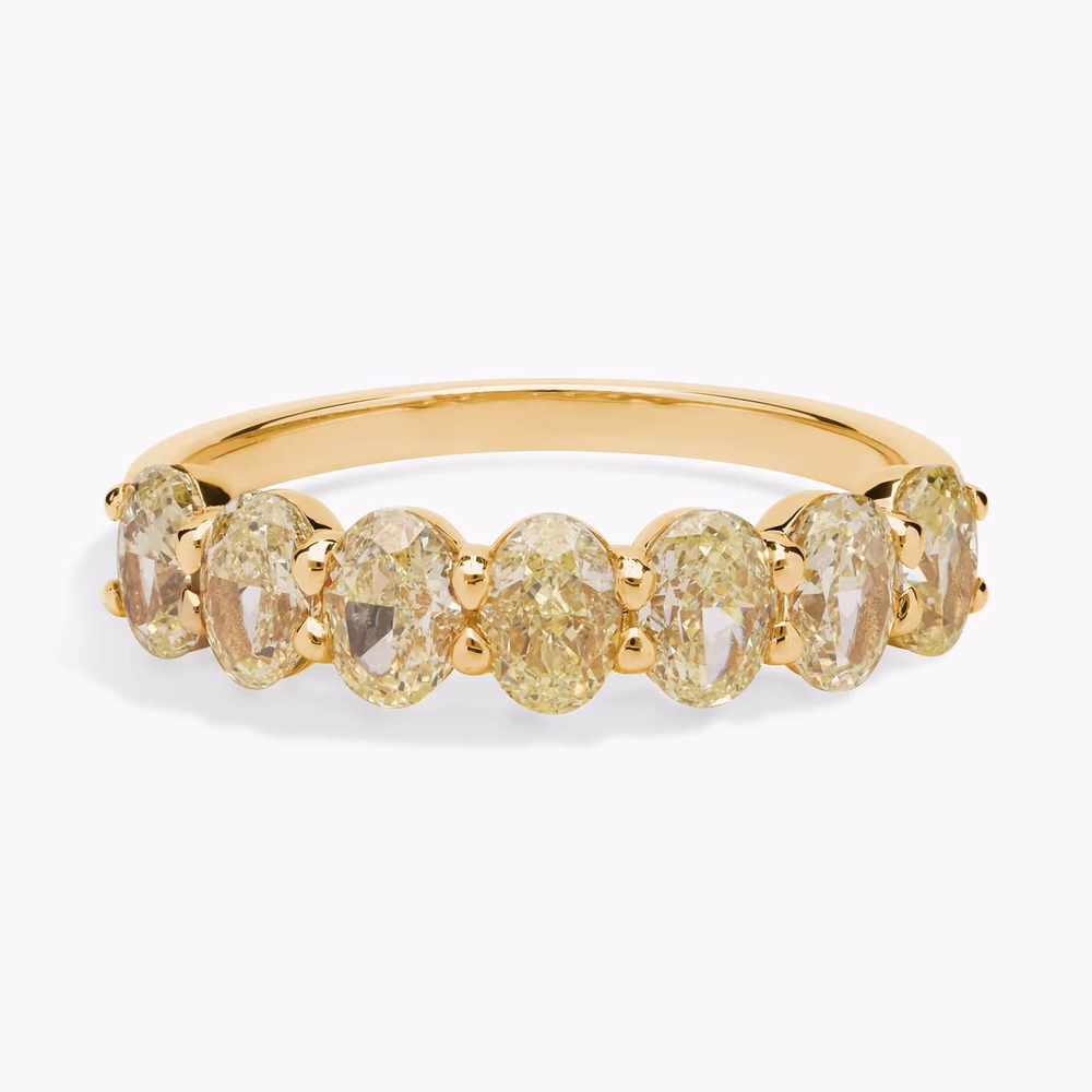 Oval diamond wedding band in yellow gold — close-up orbital view of the seven-stone oval diamond ring showing matched oval-cut diamond stones across the shank top in 14K yellow gold, bezel protection detail visible around each stone's girdle